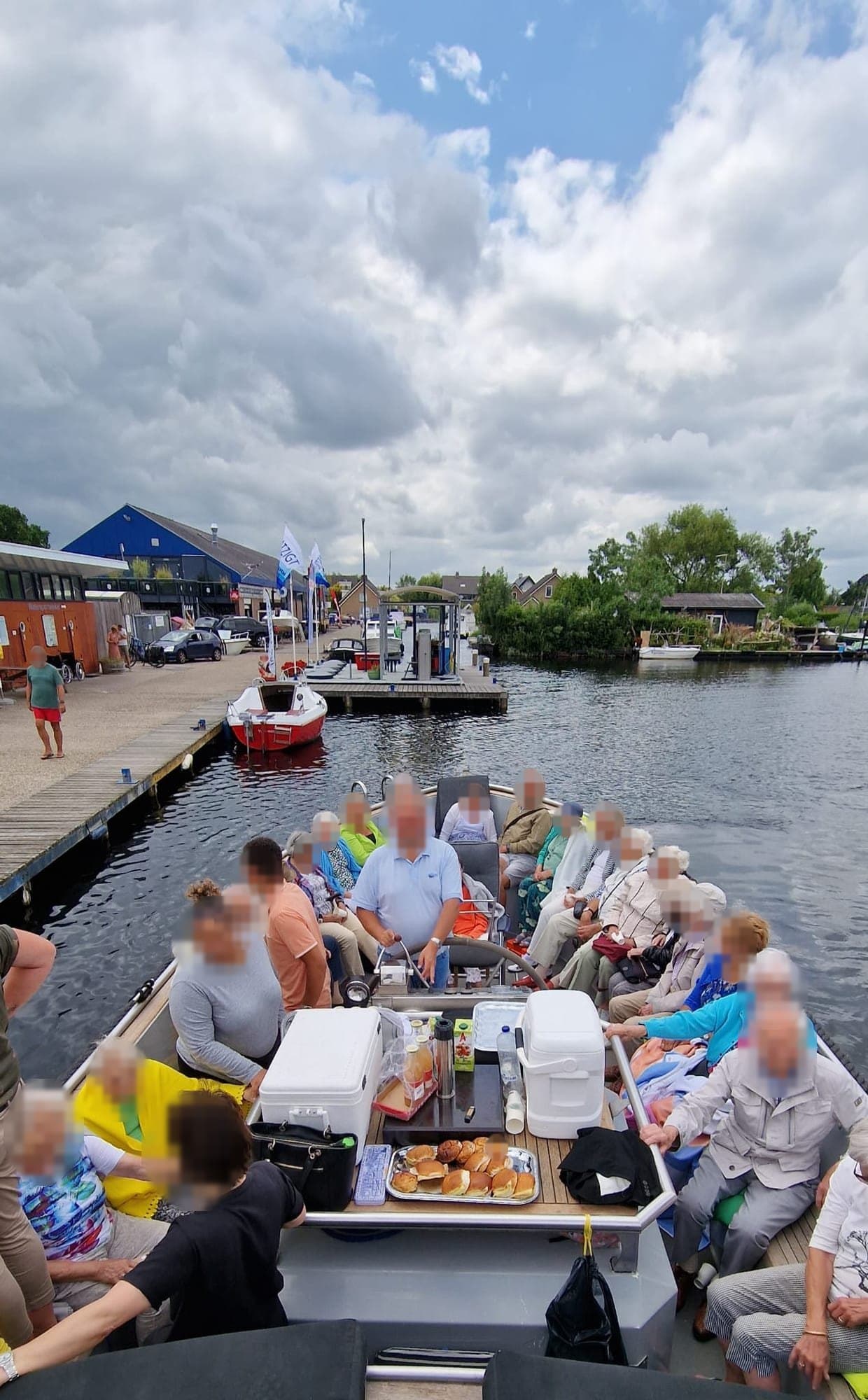 Een gezelschap ouderen aan boord van de sloep, op een zonnige dag op het water